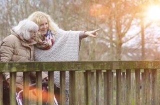Eine Frau begleitet eine Seniorin beim Spazieren